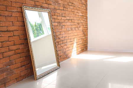 Big stylish mirror near brick wall in empty roomの写真素材
