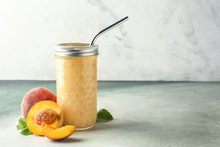Jar with fresh peach smoothie on light tableの写真素材