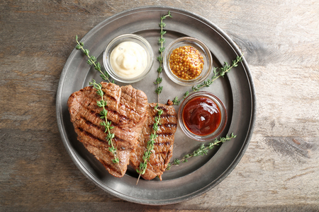 Tasty grilled steak with different sauces on metal trayの写真素材