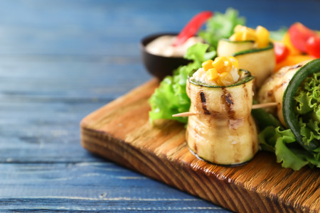 Tasty zucchini rolls with vegetables on wooden boardの写真素材