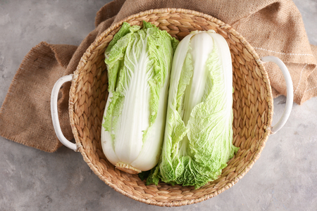 Wicker basket with fresh ripe cabbage on grey tableの写真素材