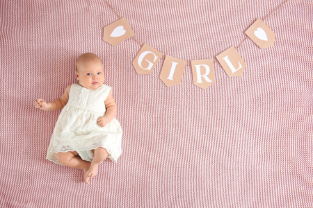 Paper garland with word GIRL and cute baby lying on bed, top viewの写真素材