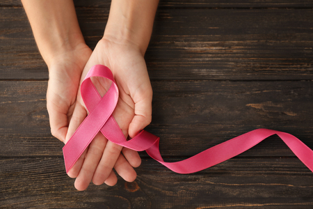 Woman holding pink ribbon on wooden background. Breast cancer conceptの写真素材