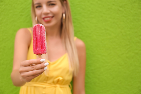 Beautiful young woman with ice cream near color wallの写真素材