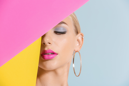 Beautiful young woman with bright pink lipstick and color paper sheets on light backgroundの写真素材