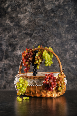Wicker basket with fresh ripe grapes on dark grey backgroundの写真素材