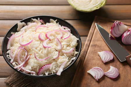 Bowl with delicious sauerkraut and onion on wooden tableの写真素材