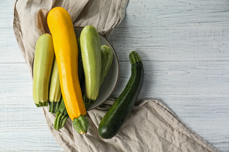 Plate with fresh zucchinis on white wooden tableの写真素材