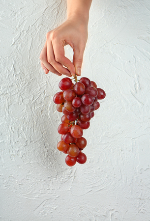 Woman holding fresh ripe grapes on white textured backgroundの写真素材