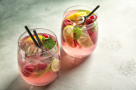 Glasses of fresh raspberry mojito on light tableの写真素材