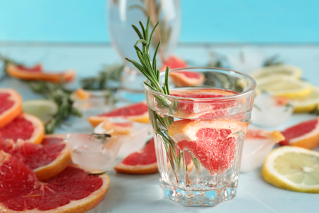 Fresh grapefruit cocktail with rosemary in glass on light tableの写真素材