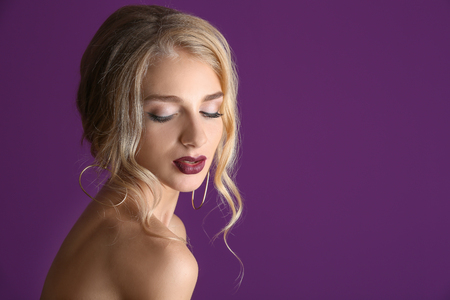 Beautiful young woman with dark lipstick on color backgroundの写真素材