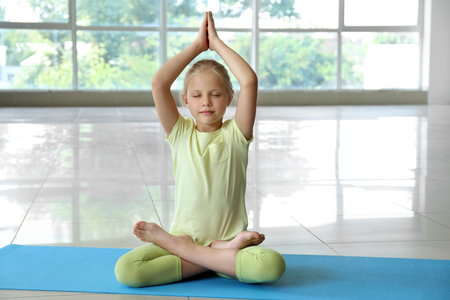 Little girl practicing yoga indoorsの写真素材