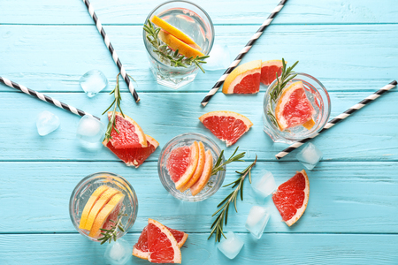 Fresh grapefruit cocktail with rosemary in glasses on color wooden tableの写真素材