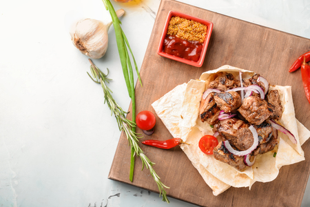 Board with delicious shish kebab and sauce on light tableの写真素材