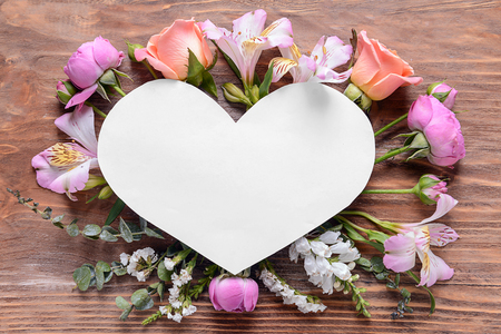 Heart shaped sheet of paper with beautiful flowers on wooden backgroundの写真素材