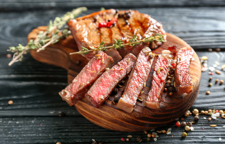 Cut grilled steak with spices on wooden boardの写真素材