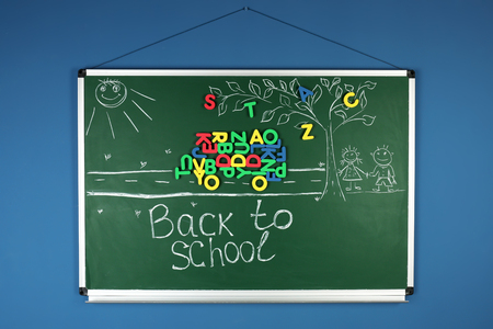 Phrase BACK TO SCHOOL with drawings on chalkboard against color backgroundの写真素材