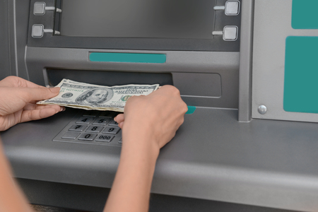Woman picking up the money from a cash machine, closeupの写真素材