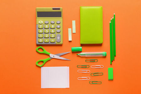 Set of school stationery with calculator on color background