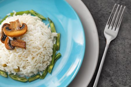 Plate with tasty boiled rice, mushrooms and green beans on grey tableの写真素材