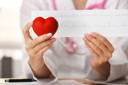 Doctor with cardiogram and red heart in clinic, closeupの写真素材