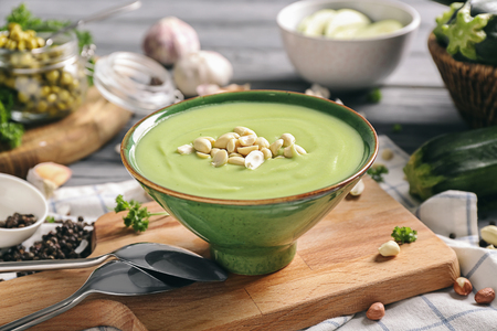 Bowl with tasty zucchini soup on wooden boardの写真素材