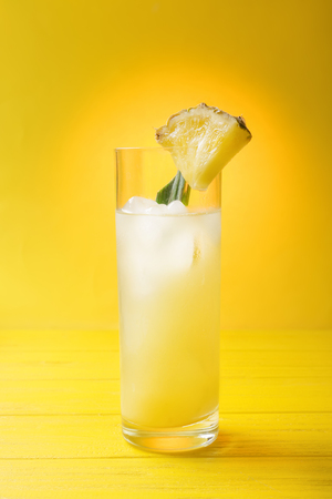 Glass of cold pineapple juice on yellow backgroundの写真素材