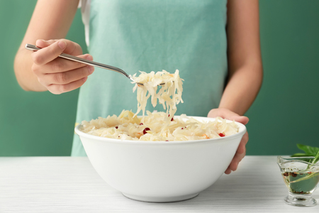 Woman eating homemade sauerkraut at white table, closeupの写真素材