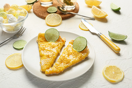 Plate with pieces of delicious lemon pie on white tableの写真素材