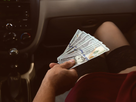 Young prostitute receiving money from client in carの写真素材