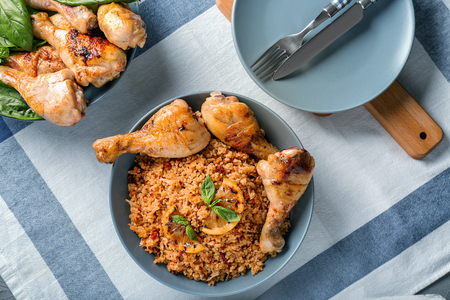 Tasty boiled rice with chicken drumsticks in bowl on tableの写真素材