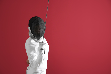Young female fencer on color background