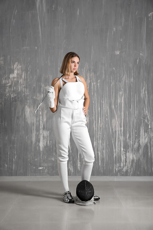 Young female fencer near grunge wallの写真素材
