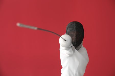 Young female fencer on color background