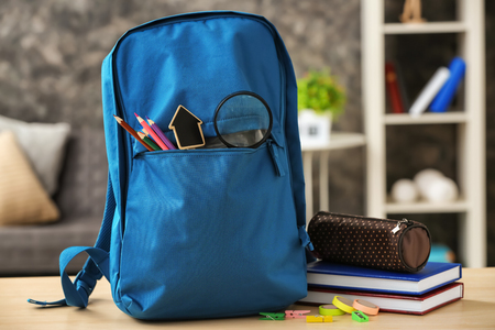 Backpack with school supplies on table indoorsの写真素材