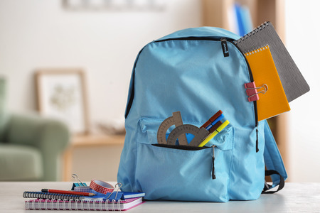 Backpack with school supplies on table indoorsの写真素材