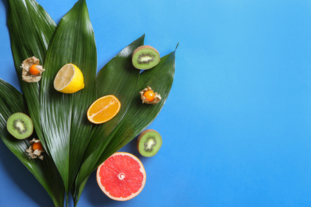 Various delicious exotic fruits with tropical leaves on color backgroundの写真素材