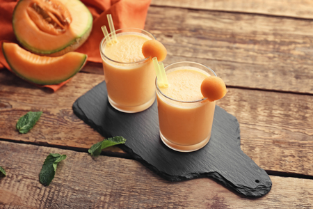 Glasses with tasty melon smoothie on wooden tableの写真素材