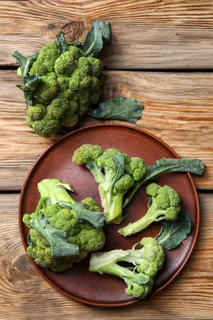 Plate with ripe broccoli on wooden tableの写真素材