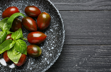 Plate with delicious tomatoes and fresh basil on wooden tableの写真素材