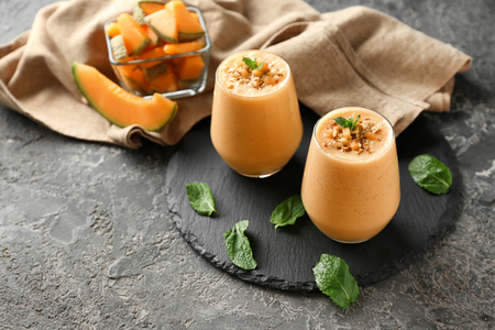 Glasses of tasty melon smoothie on grunge tableの写真素材