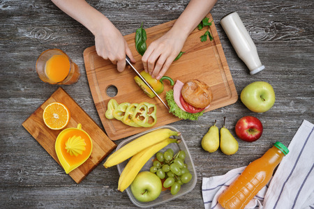 Mother cutting pepper for school lunch on tableの写真素材