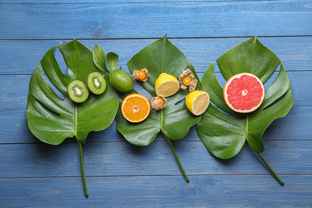 Various delicious exotic fruits with tropical leaves on color wooden backgroundの写真素材