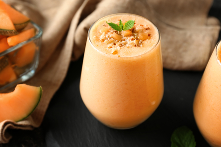 Glass of tasty melon smoothie on tableの写真素材