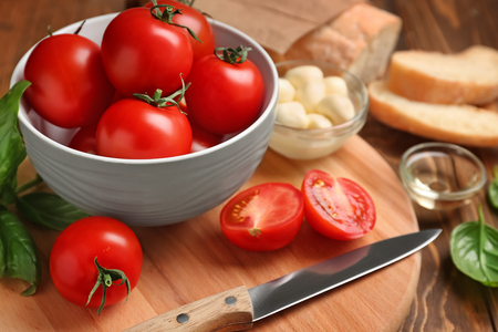 Bowl with delicious tomatoes on boardの写真素材