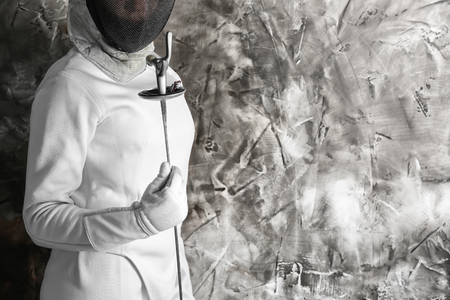 Young female fencer against grunge wall