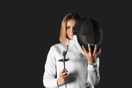 Young female fencer on dark background