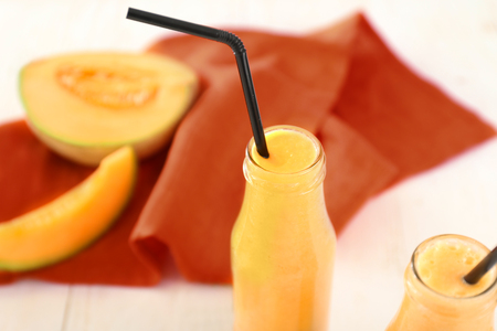 Bottles with delicious melon smoothie on white tableの写真素材