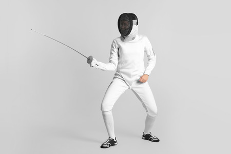 Young female fencer on light backgroundの写真素材